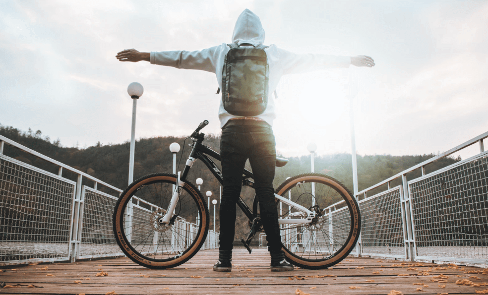 Man on a dock with his bicycle and his arms stretched out