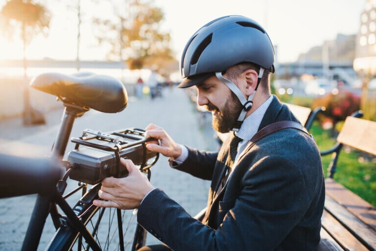 Hipster businessman commuter setting up electric bicycle when traveling home from work in city