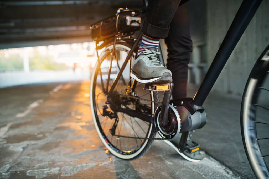 Midsection of businessman commuter with electric bicycle traveling from work in city