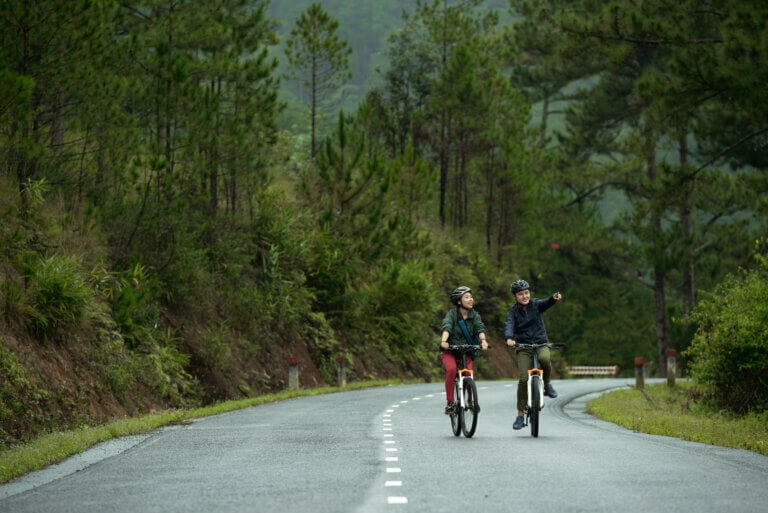 Traveling couple riding their bicycles down a forest road