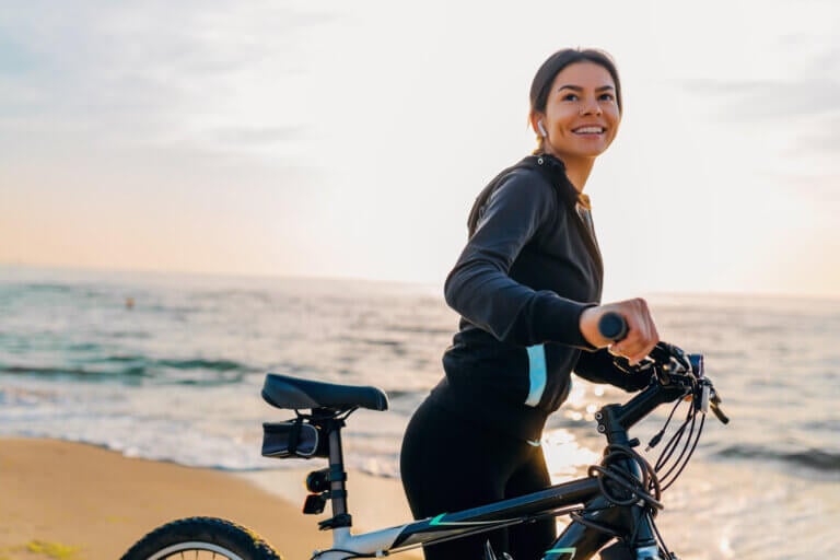 Young woman riding her bicycle at sunrise on the beach