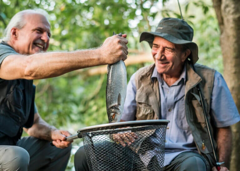 Two men looking at a fish they caught and smiling